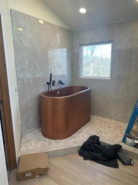 Bathroom remodel with a copper freestanding soaking tub on a hexagon mosaic platform