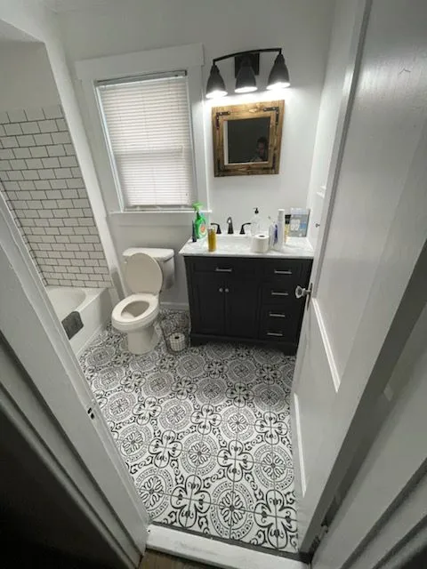 Small bathroom with a patterned tile floor, dark vanity and white subway tile tub surround