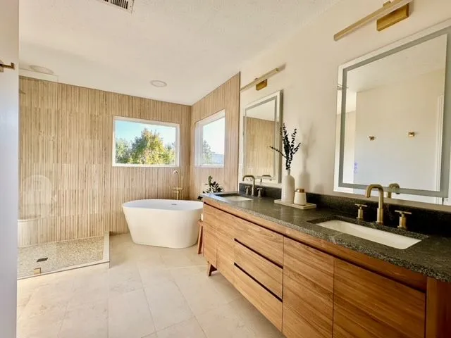 Bathroom remodeling near Dayton, OH — a freestanding tub, walnut double vanity and fluted tile feature wall
