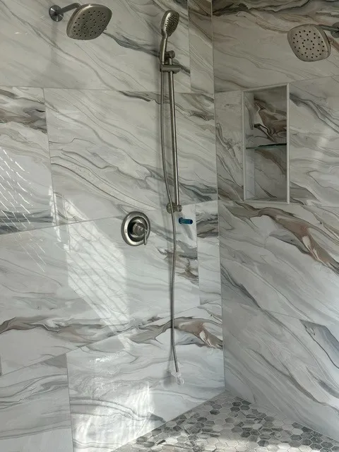 Double shower with twin rain heads and a handheld set against marbled porcelain slab tile