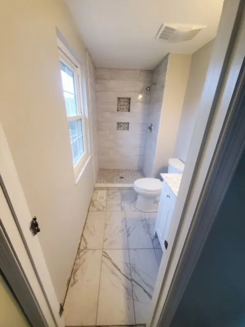 Small bathroom remodel with marble-look tile floor and a walk-in shower