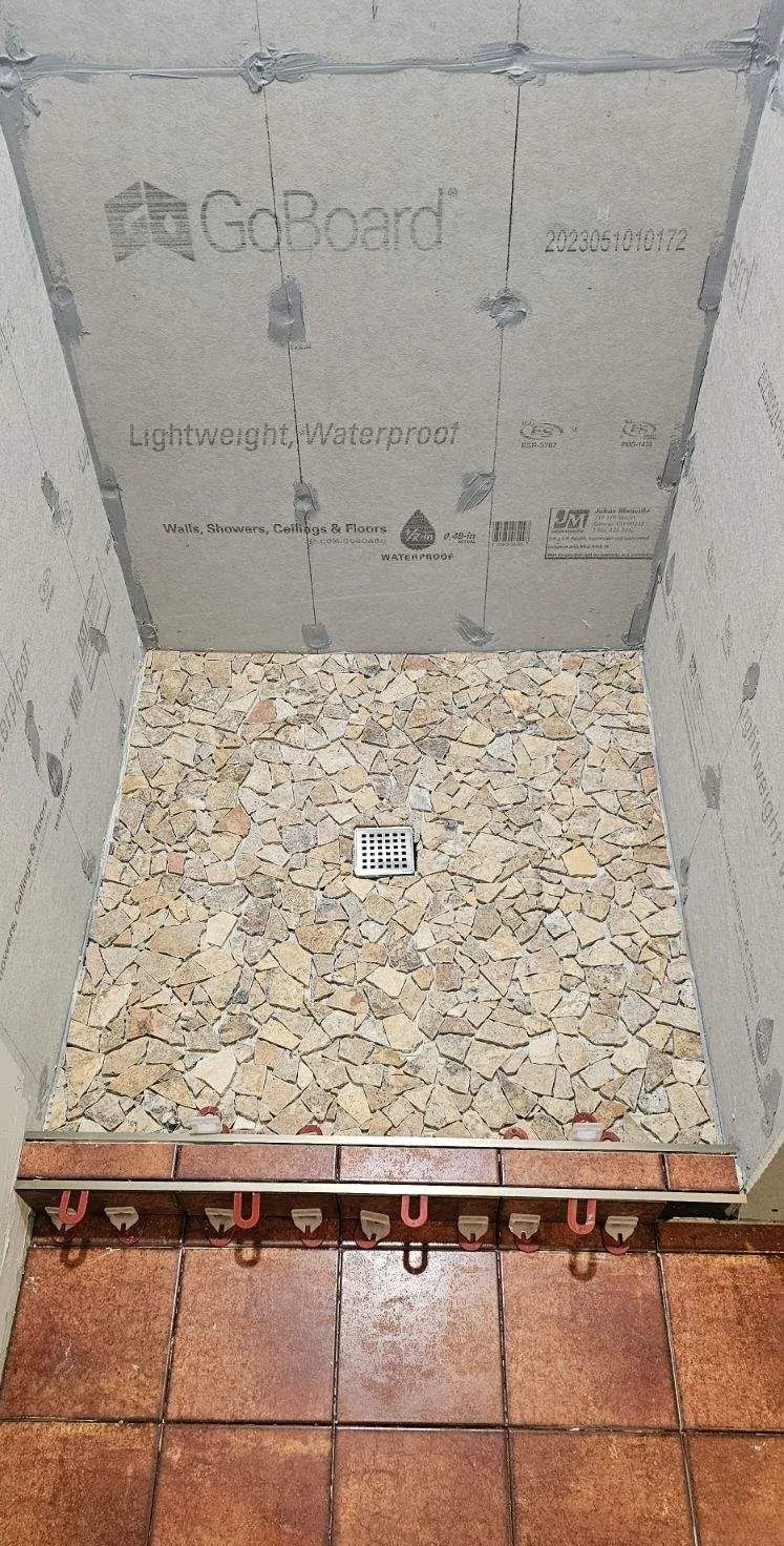Shower pan waterproofing and stone tile installation during a bathroom remodel