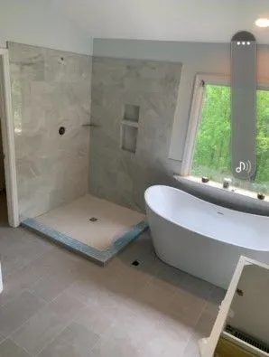 Bathroom remodel with a marble tile shower and a freestanding slipper tub