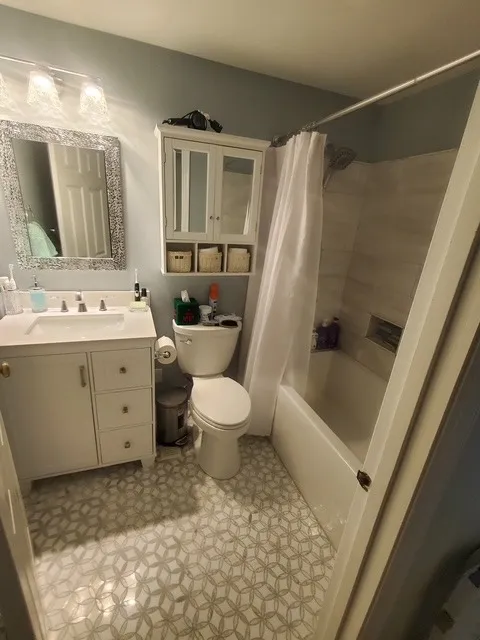 Compact full bathroom with a geometric patterned floor and a white vanity