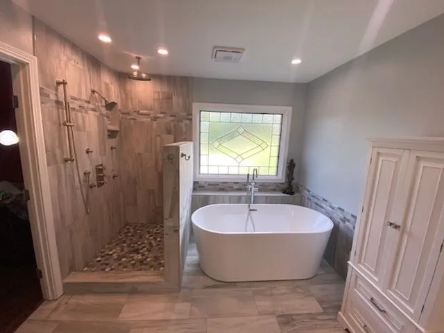 Bathroom remodeling with a walk-in tile shower, freestanding soaking tub and a leaded glass window