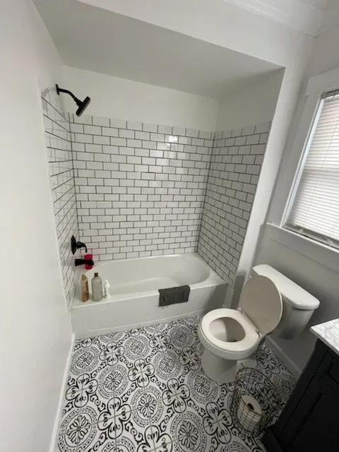 Bathroom remodel with white subway tile, black fixtures and a patterned encaustic floor