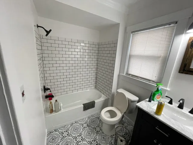 Subway tile tub surround above a patterned tile floor