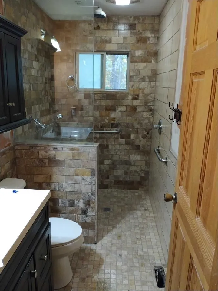 Accessible bathroom remodel with a low-threshold travertine shower and grab bars