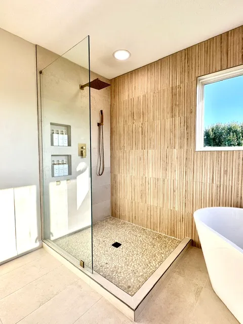 Travertine shower next to a built-in soaking tub
