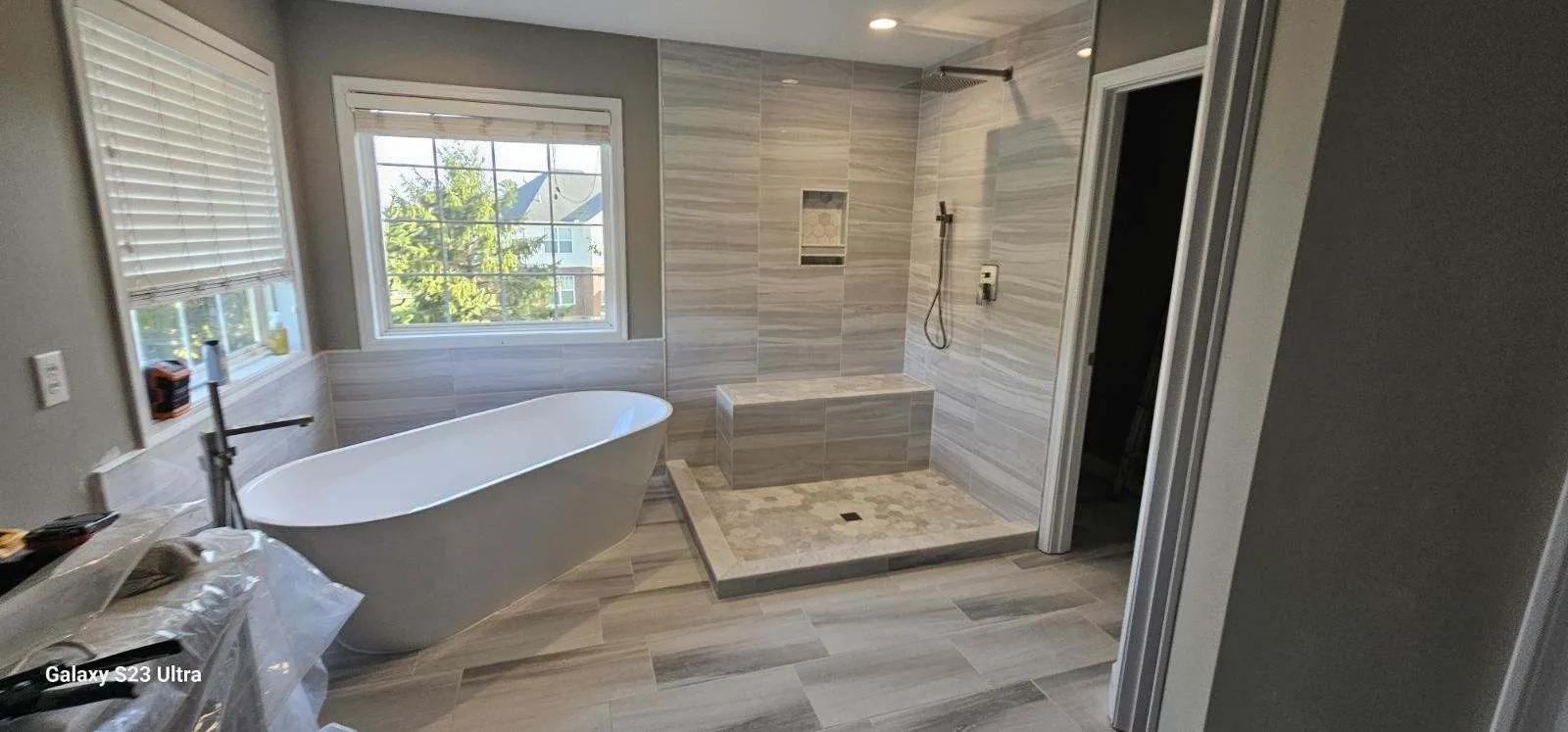 Freestanding tub beside a walk-in shower in a wide marble-tiled bathroom