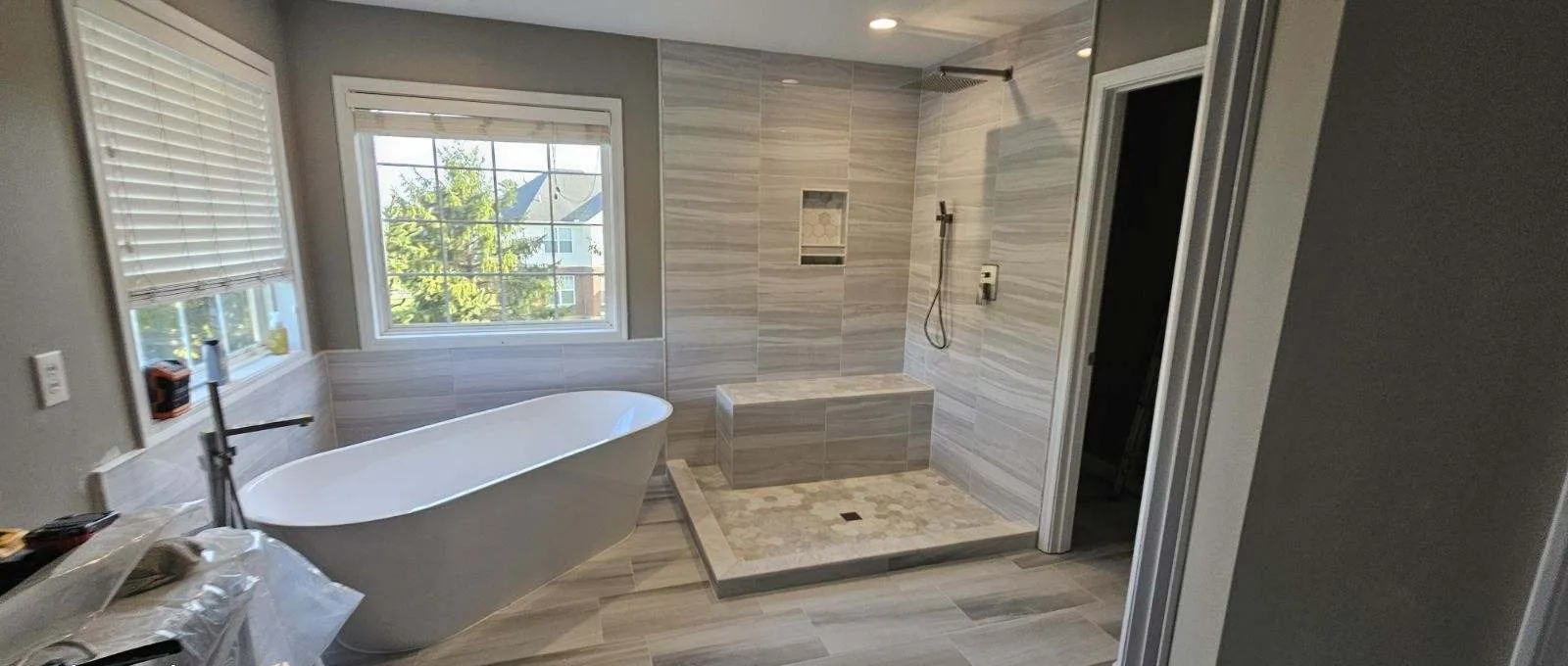 Bathroom remodeling Dayton OH — a freestanding soaking tub beside a large walk-in shower with a tiled bench
