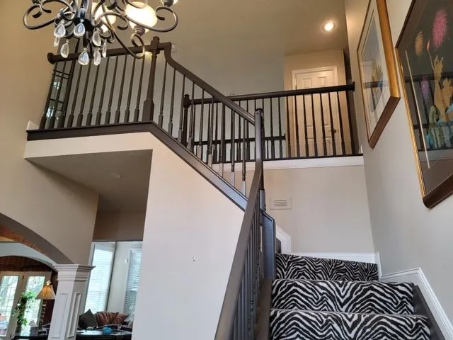 Two story entry with a dark stained staircase, iron balusters and a chandelier