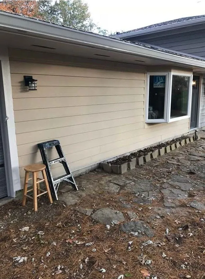 House exterior with new beige siding, a bay window and a stone path