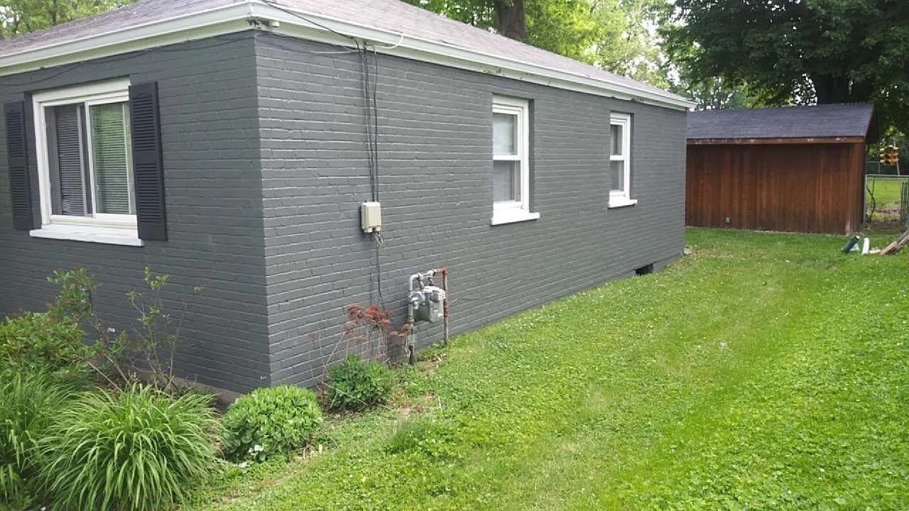 Exterior painting services — a brick house painted charcoal grey with white trim