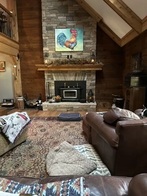 Great room with a stone fireplace, vaulted pine ceiling and exposed beams