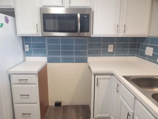 Small kitchen remodel with white cabinets and a blue subway tile backsplash