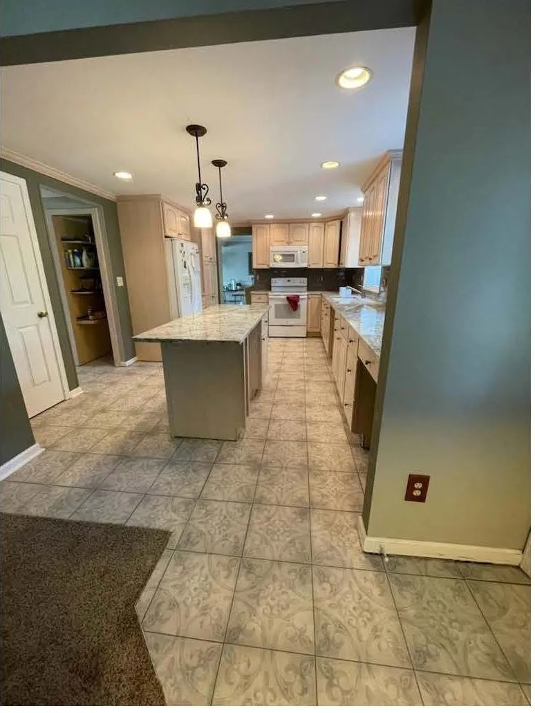 Remodeled kitchen with maple cabinets, a granite island and patterned ceramic tile floor