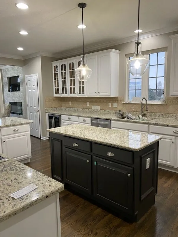 Kitchen remodeling in Hillsboro, OH — white cabinets, a black island and granite counters under glass pendant lights