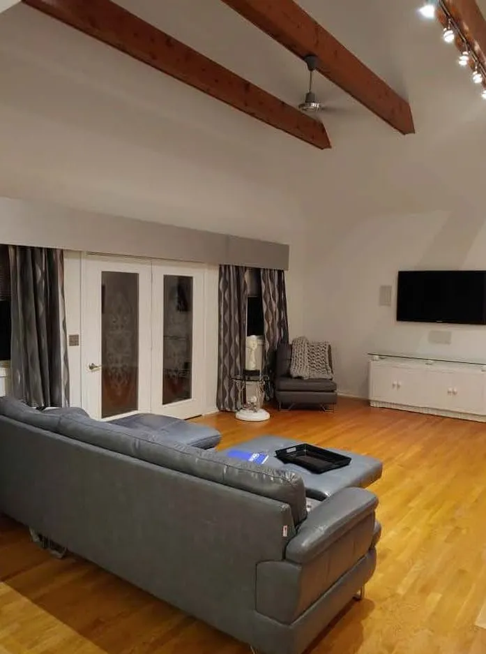 Finished upper floor living space with exposed beams and hardwood flooring