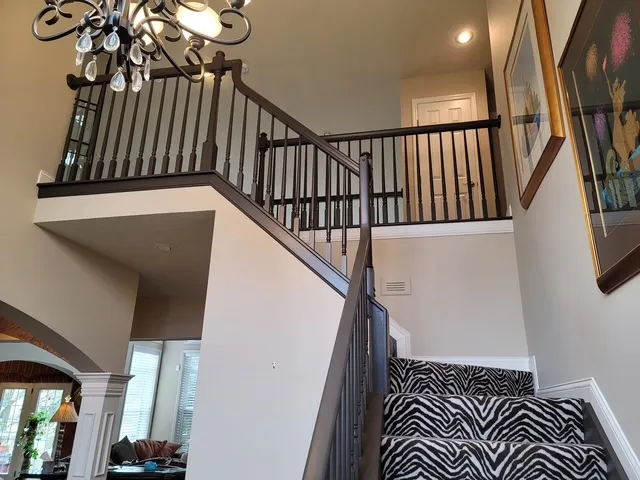 Stair hall seen from the landing, patterned runner on the treads